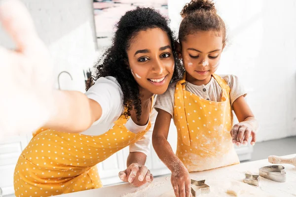 Telecamera punto di vista di sorridente afro americano madre e figlia preparare i biscotti con stampi in cucina — Foto stock