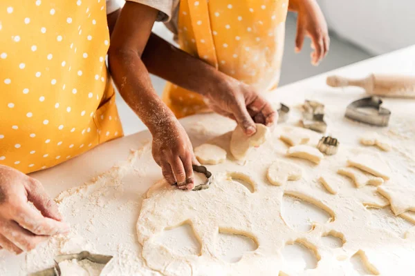 Immagine ritagliata di madre e figlia afro-americana che preparano i biscotti con stampi in cucina — Foto stock