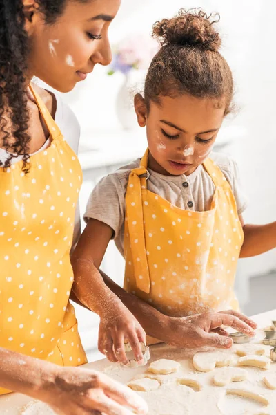 African american mother and daughter preparing cookies with dough molds in kitchen — Stock Photo