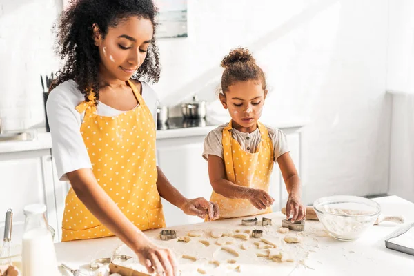 African american mother and daughter preparing cookies with molds together in kitchen — Stock Photo