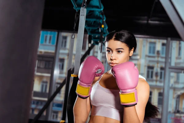 Приваблива сильна дівчина в захисних рукавичках практикує бокс в спортзалі — стокове фото