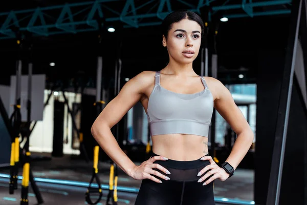 Atractiva chica fuerte de pie akimbo en el gimnasio de fitness - foto de stock