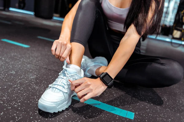Teilansicht sportlicher Mädchen, die Schnürsenkel in Fitnessstudio binden — Stockfoto