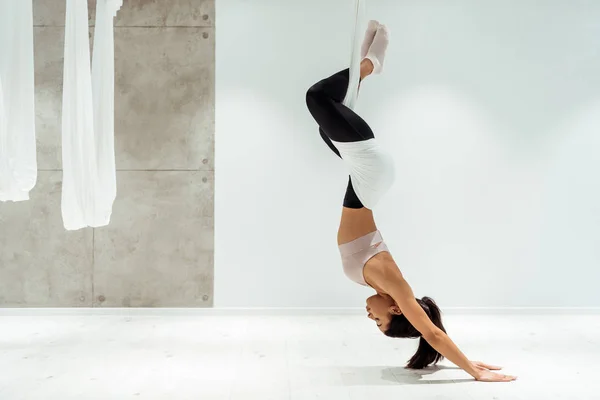 Спортивная девушка расслабляется во время практики антигравитационной йоги и инверсии позиции в студии йоги — стоковое фото