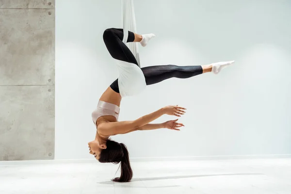 Hermosa chica relajada practicando yoga antigravedad en posición de inversión en estudio - foto de stock