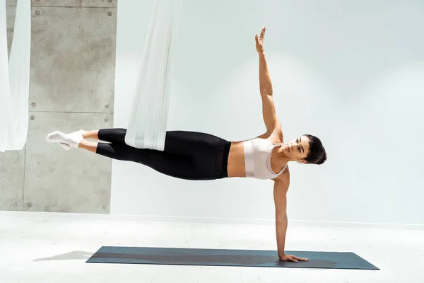 Atractiva fuerte hembra practicando yoga antigravedad en hamaca en estudio - foto de stock