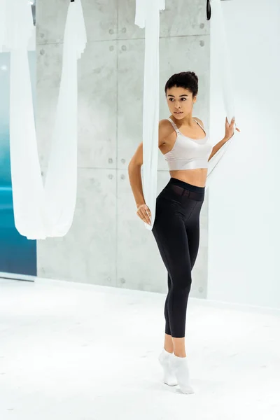 Chica deportiva atractiva practicando yoga antigravedad con hamaca en el estudio - foto de stock
