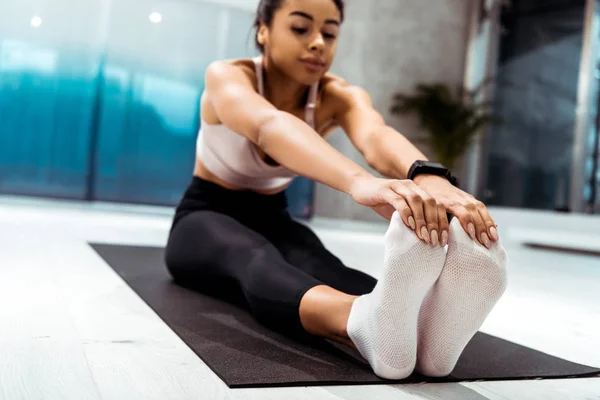 Joven chica deportiva atractiva limbering en el centro deportivo - foto de stock