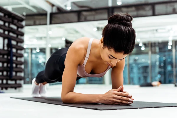 Beautiful sportive girl doing plank on mat  in fitness gym — Stock Photo