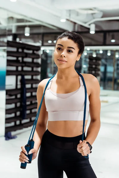 Attractive sportive girl standing with jump rope in fitness gym — Stock Photo
