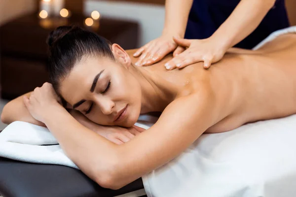 Attractive young woman with closed eyes having massage therapy in spa — Stock Photo
