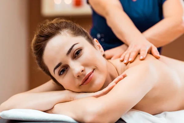 Привлекательная молодая женщина улыбается перед камерой во время массажа в спа — стоковое фото