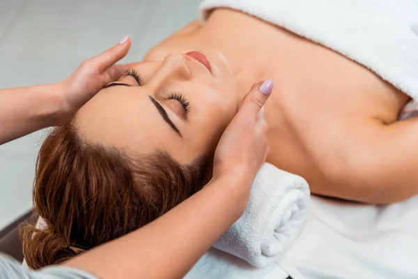 Tiro recortado de mujer joven teniendo masaje facial en el salón de spa - foto de stock