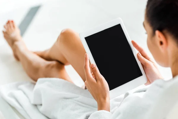 Imagen recortada de la mujer en albornoz utilizando tableta digital con pantalla en blanco en el spa - foto de stock