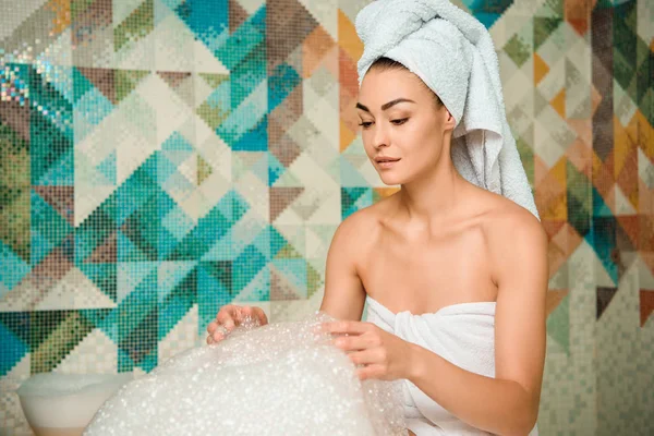 Jeune femme regardant la mousse dans le bain turc — Photo de stock