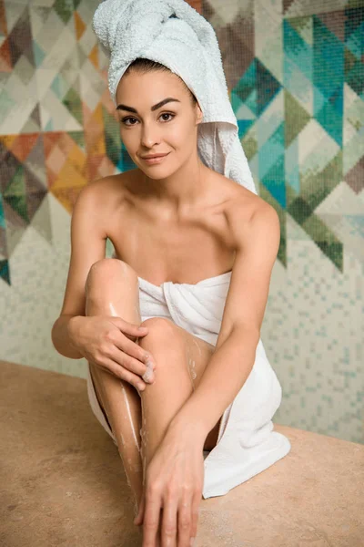 Beautiful young woman sitting on hammam table and smiling at camera — Stock Photo