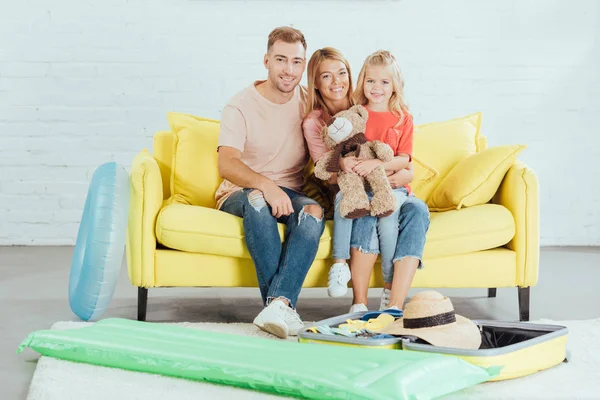 Familia sentada en el sofá y embalaje para vacaciones de verano familiares - foto de stock