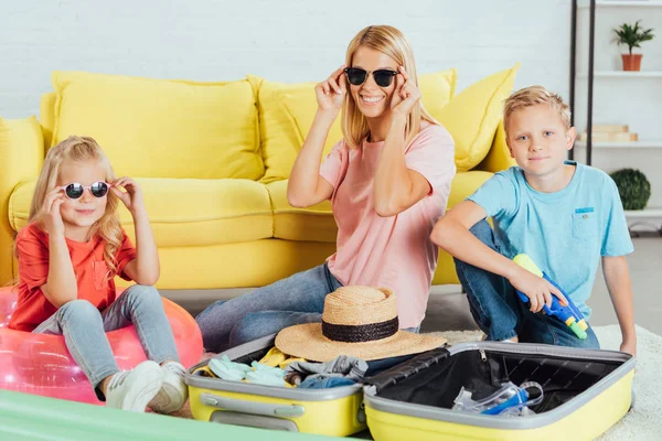 Cheerful family packing baggage for for summer vacation, having fun and trying on glasses, travel concept — Stock Photo