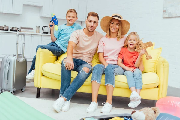 Glückliche Familie blickt in die Kamera und ruht sich nach dem Packen für den Sommerurlaub auf dem Sofa aus, Reisekonzept — Stockfoto