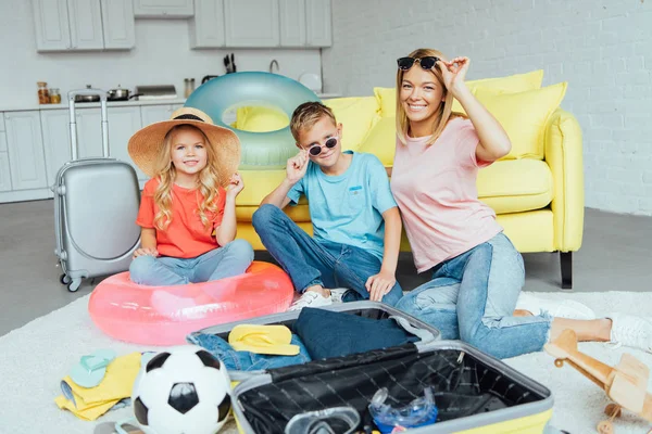 Familia feliz probándose accesorios de playa y embalaje para vacaciones de verano, concepto de viaje - foto de stock