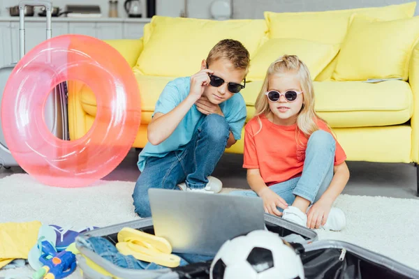 Kinder in Brille mit Laptop und Verpackung für Familien-Sommerurlaub, Reisekonzept — Stockfoto