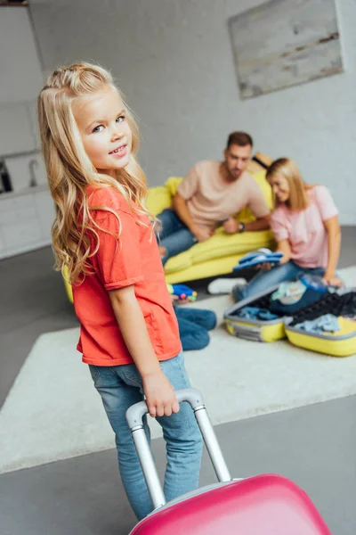 Kid holding suitcase while family packing for summer vacation on background, travel concept — Stock Photo