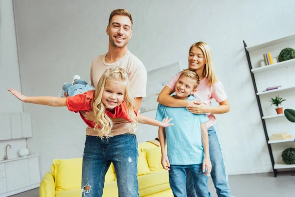Happy father playing and having fun with daughter and smiling mother hugging son — Stock Photo