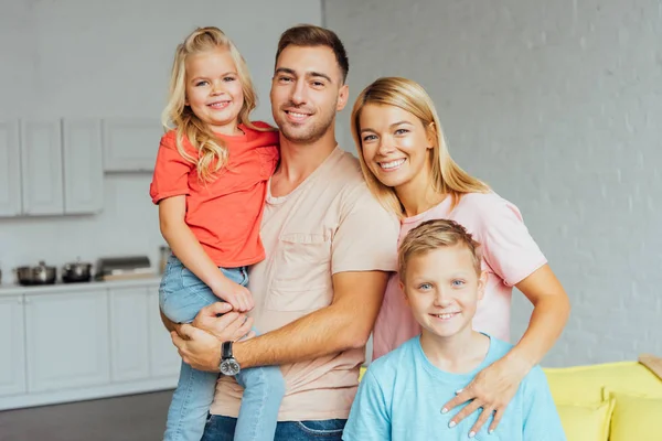 Glückliche Familie in lässiger Kleidung, die sich umarmt und in die Kamera schaut — Stockfoto