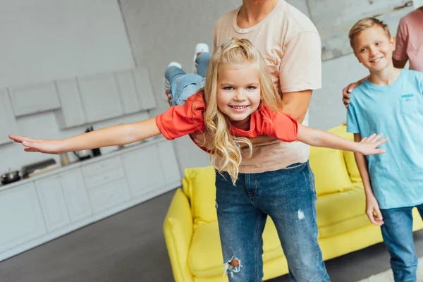 Pai brincando com a filha feliz com o filho no fundo — Fotografia de Stock