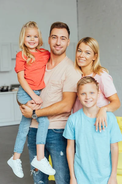 Fröhliche Familie in lässiger Kleidung, die sich umarmt und in die Kamera blickt — Stockfoto