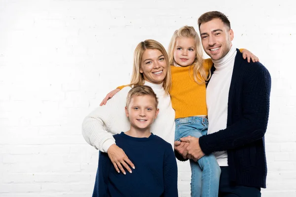 Famille souriante en vêtements décontractés étreignant et regardant la caméra sur fond blanc — Photo de stock