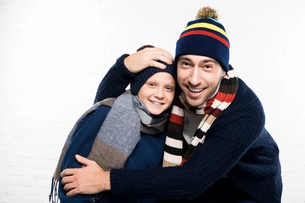 Sonrientes padre e hijo en ropa de invierno sobre fondo blanco mirando a la cámara - foto de stock