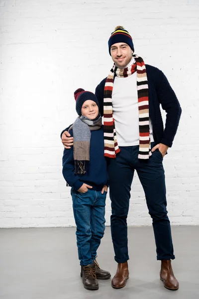 Smiling father and son in winter clothes on white background looking at camera — Stock Photo