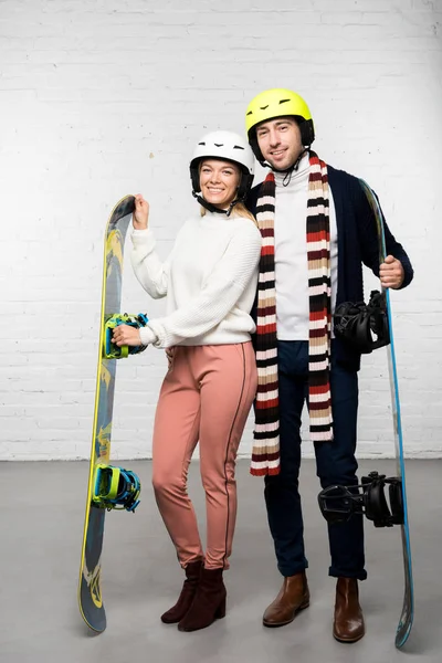 Esposo y esposa con tablas de snowboard y cascos de snowboard listos para las vacaciones de invierno - foto de stock