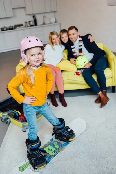 Criança em snowboard posando em primeiro plano, enquanto a família feliz ter grande momento e embalagem para férias de inverno — Fotografia de Stock