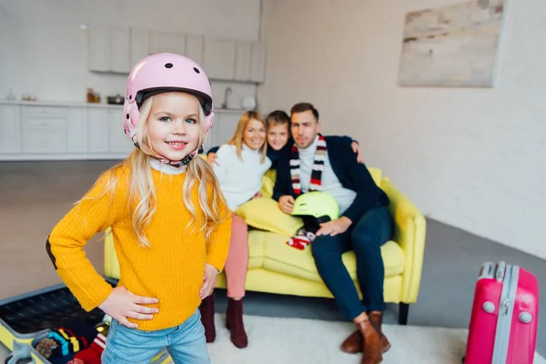 Kid on snowboard posing on foreground while happy family having great time and packing for winter holidays — Stock Photo