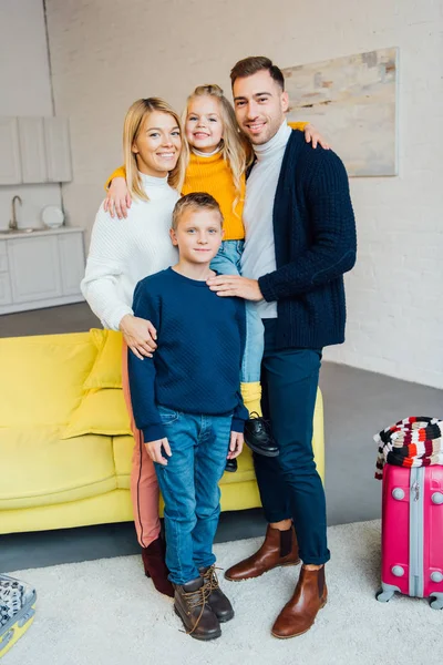 Happy family ready for winter holidays and looking at camera with packed suitcase, travel concept — Stock Photo