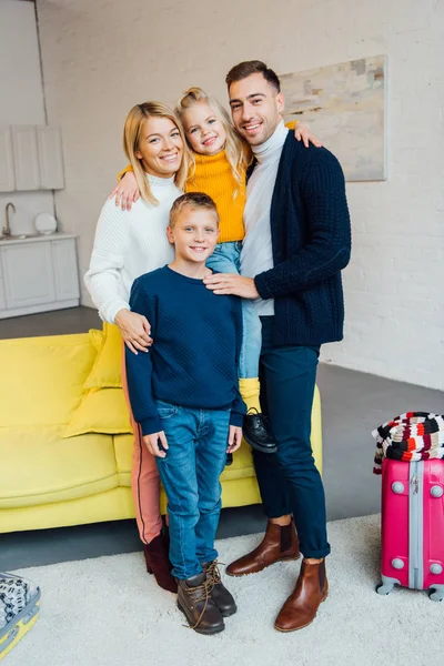 Glückliche Familie bereit für den Winterurlaub und Blick in die Kamera mit gepacktem Koffer, Reisekonzept — Stockfoto