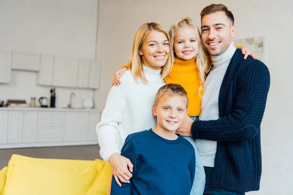 Família feliz em roupas casuais abraçando e olhando para a câmera — Fotografia de Stock