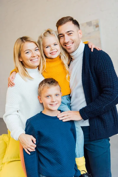 Família feliz em roupas casuais abraçando e olhando para a câmera — Fotografia de Stock