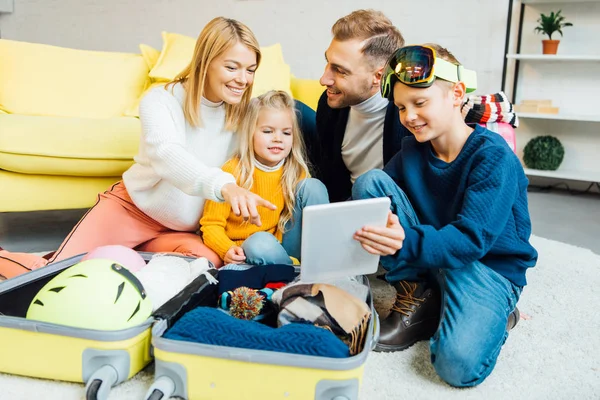 Famiglia felice avendo grande tempo, utilizzando tablet digitale e imballaggio per le vacanze invernali — Foto stock