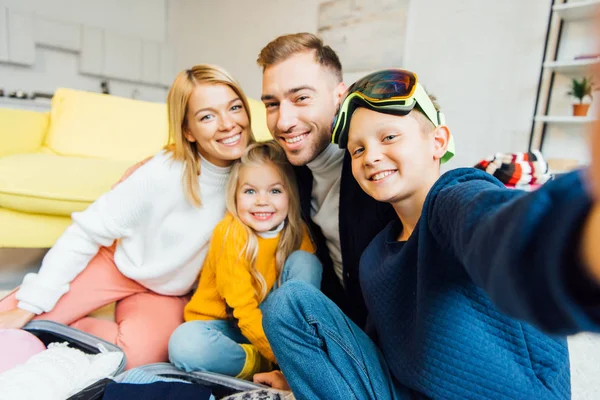 Happy family taking selfie while packing for winter holidays — Stock Photo