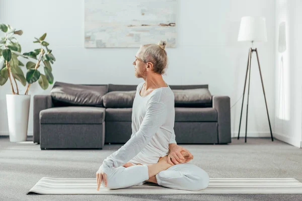 Flexibler, athletischer Mann, der zu Hause Yoga auf Matte praktiziert — Stockfoto