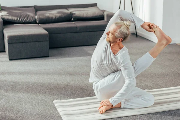 Високий кут зору на атлетичного гнучкого дорослого чоловіка, який практикує йогу вдома — стокове фото