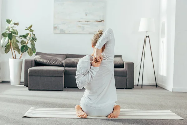 Rückansicht eines Mannes, der zu Hause Yoga mit den Händen praktiziert — Stockfoto