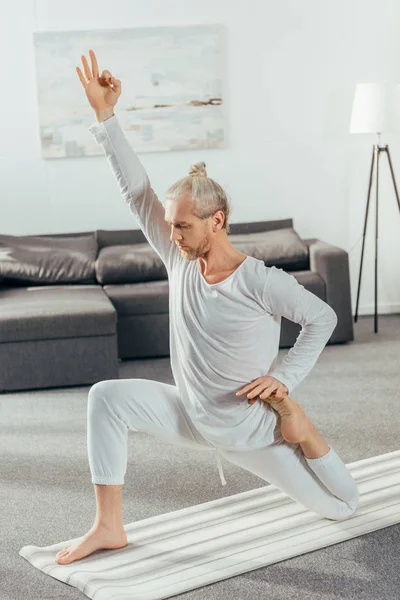 Athletische flexible erwachsene Mann praktiziert Yoga auf Matte zu Hause — Stockfoto