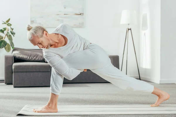 Homme debout dans la pose d'angle latéral lié sur tapis de yoga à la maison — Photo de stock