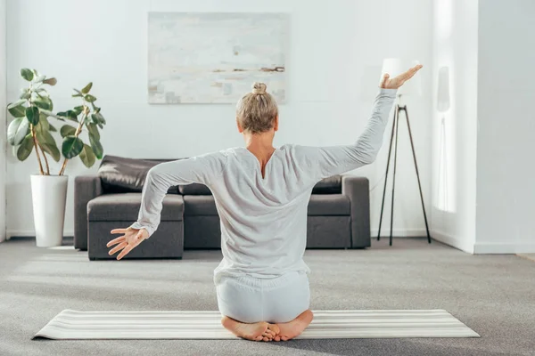 Vista posteriore di uomo adulto in abbigliamento sportivo praticare yoga sul tappeto a casa — Foto stock