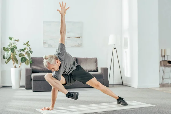 Flexibler sportlicher Mann, der zu Hause auf der Yogamatte trainiert — Stockfoto