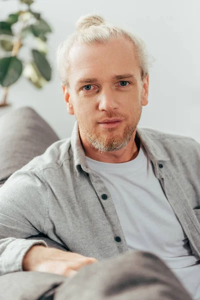 Porträt eines gut aussehenden erwachsenen Mannes, der auf der Couch sitzt und in die Kamera schaut — Stockfoto